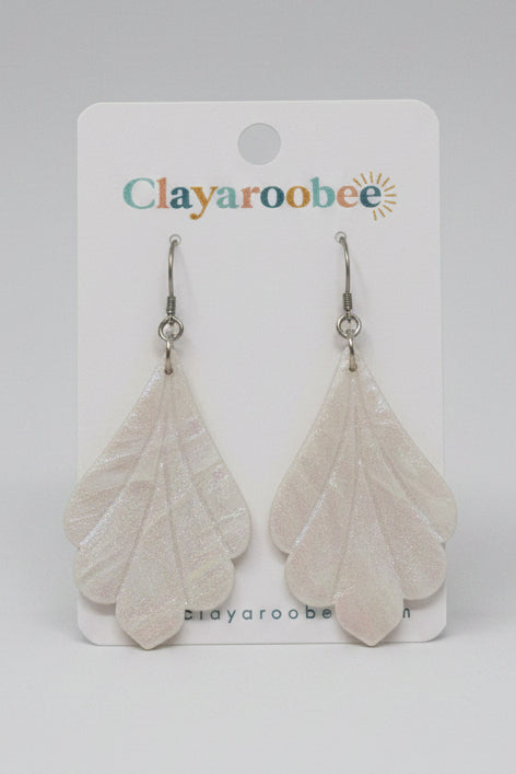 A pair of marbled design white clay dangle earrings on a white Clayaroobee brand display card