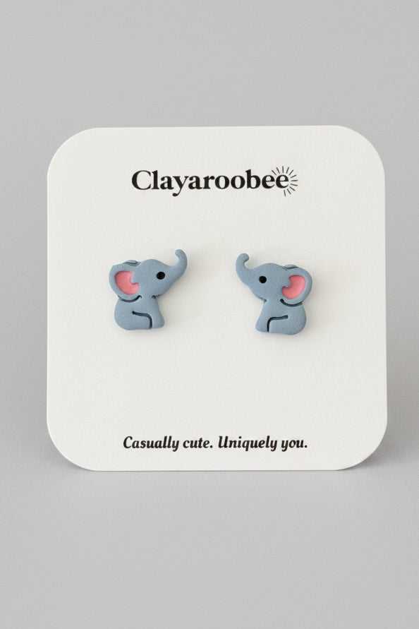 A pair of small elephant stud earrings on a white display card. The card is printed with the brand name 'Clayaroobee' 