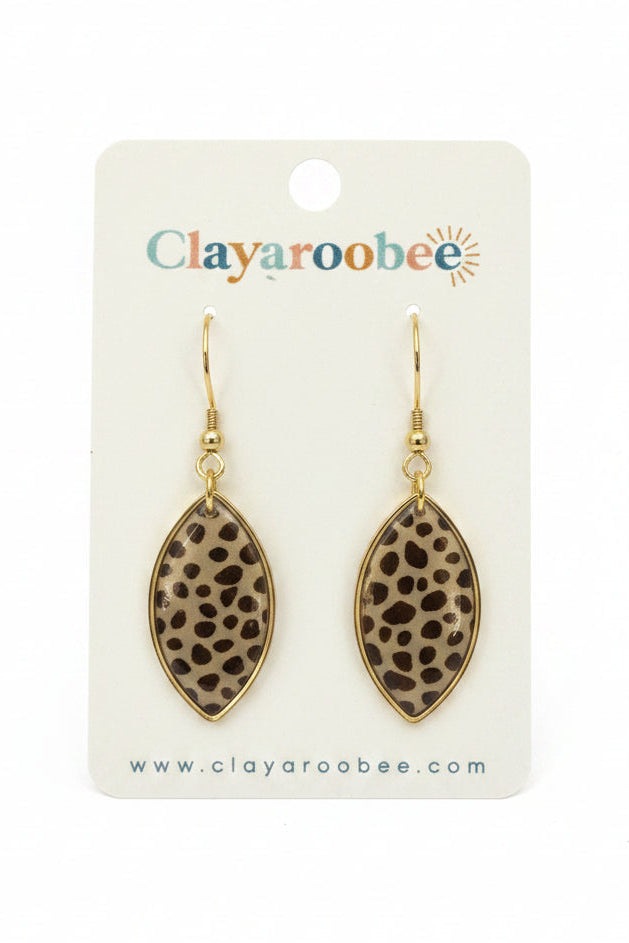 A pair of clay earrings with a brown and black leopard print pattern, suspended from gold-toned hooks on a white display card branded 'Clayaroobee'. 