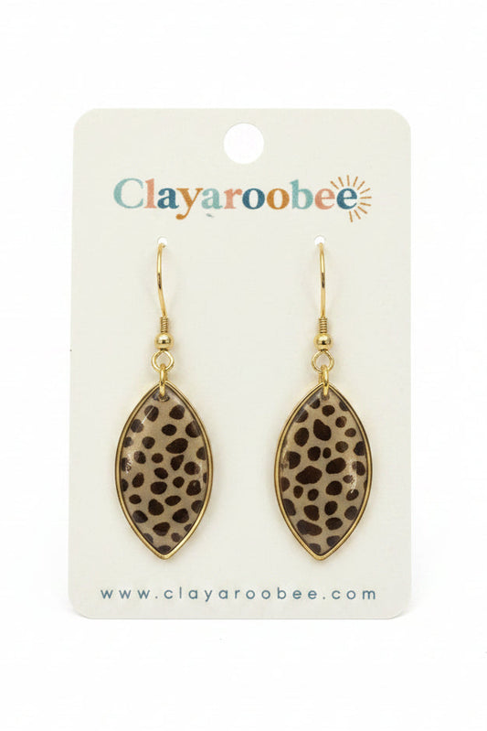 A pair of clay earrings with a brown and black leopard print pattern, suspended from gold-toned hooks on a white display card branded 'Clayaroobee'. 