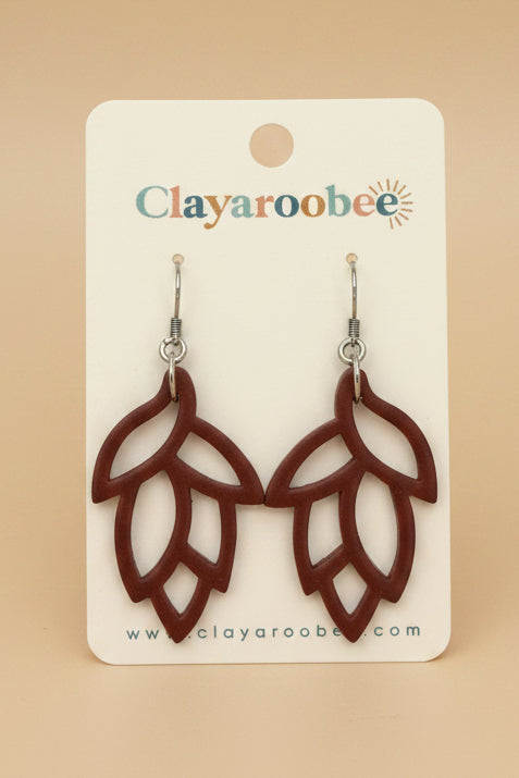 A pair of brown leaf-shaped dangle earrings displayed on a white Clayaroobee backing card
