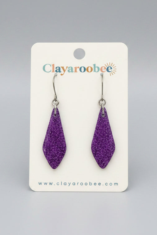Purple glitter teardrop-shaped drop earrings on a white Clayaroobee display card