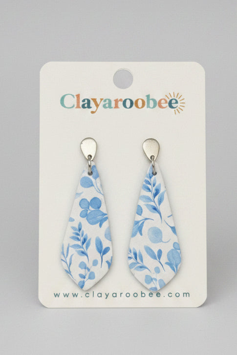 Teardrop-shaped dangle earrings with a blue floral pattern on a white background, displayed on a white Clayaroobee card.